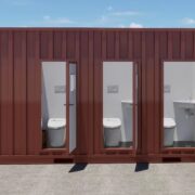 Container. På langsiden: 4 åpne dører, som fører til avlukker med toalett og vaskeservant.